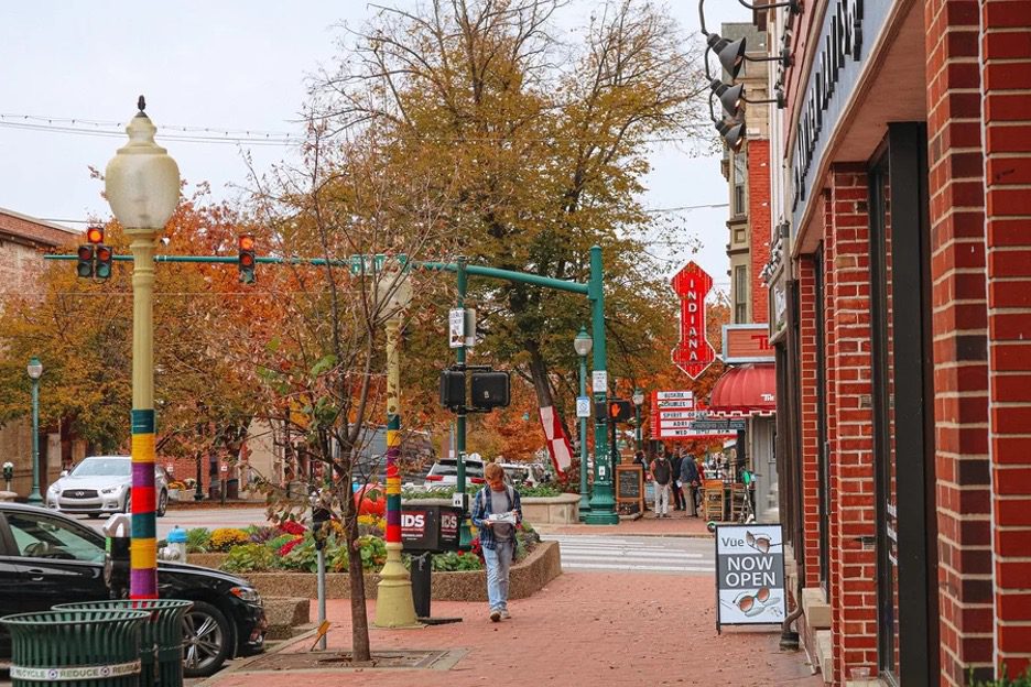 Downtown Bloomington, Indiana street with shops, sidewalks, and fall foliage.