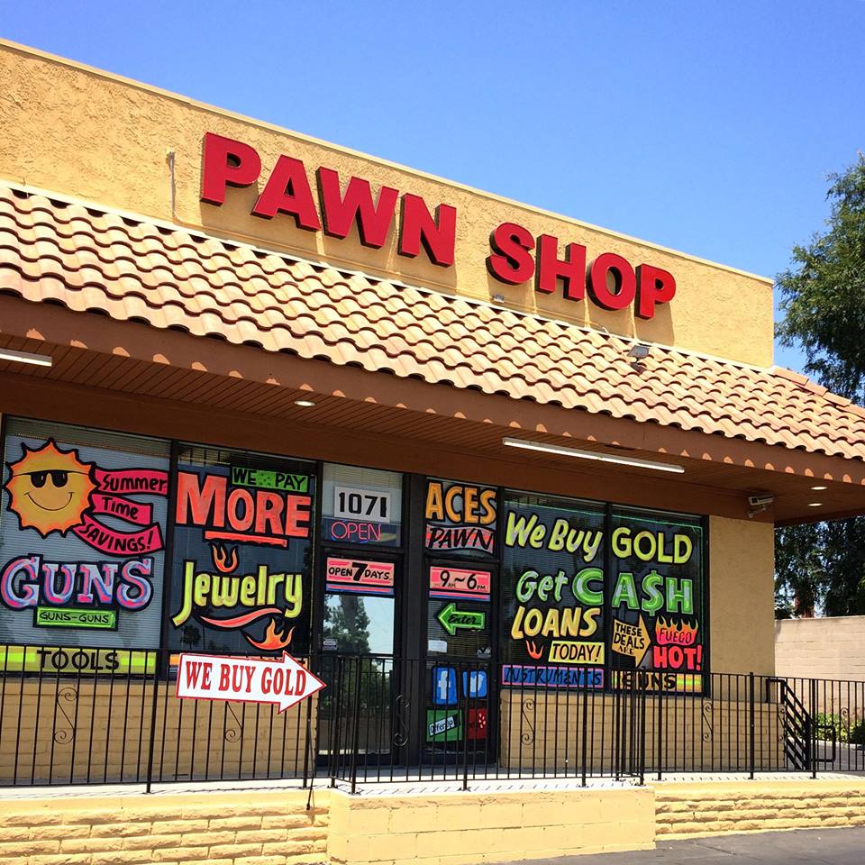 Exterior of a pawn shop with a large “Pawn Shop” sign and window displays advertising cash loans, gold buying, jewelry, and tools.